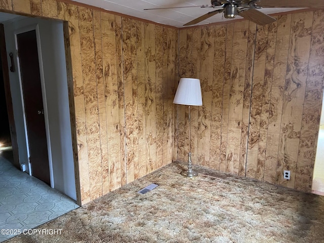 empty room featuring visible vents, wood walls, and ceiling fan
