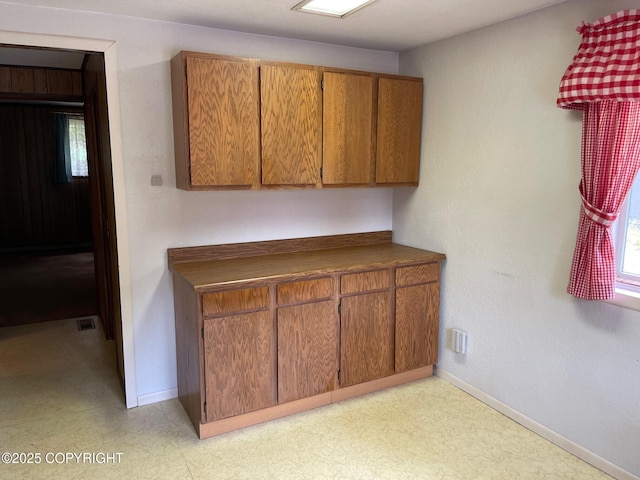 kitchen featuring brown cabinets, dark countertops, baseboards, and light floors