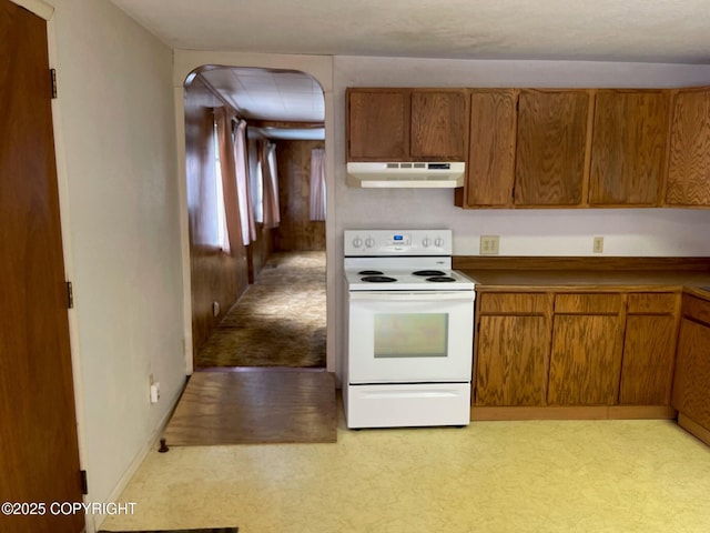 kitchen featuring brown cabinets, white electric stove, under cabinet range hood, arched walkways, and baseboards