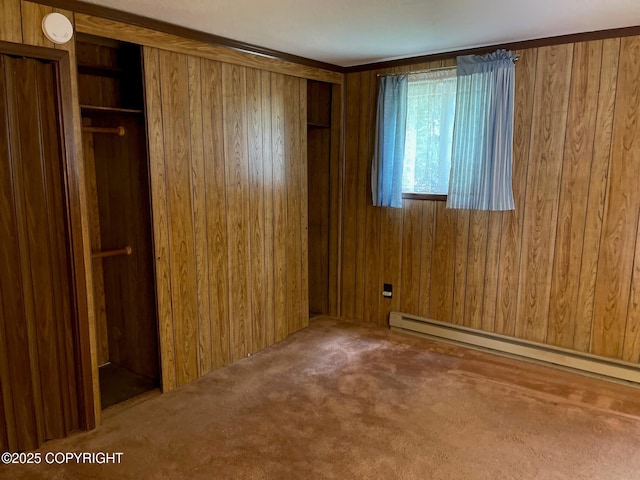 unfurnished bedroom featuring baseboard heating, wood walls, and carpet floors
