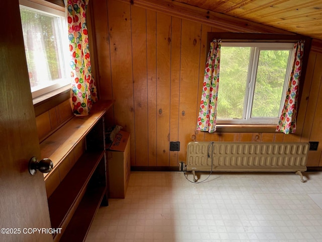 interior space featuring radiator heating unit, wooden walls, light floors, and wood ceiling