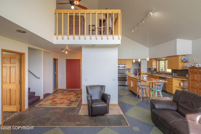 2435 Paradise Pl, Homer, AK 99603 - living area featuring track lighting, high vaulted ceiling, a ceiling fan, stairs, and baseboards