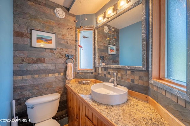 2435 Paradise Pl, Homer, AK 99603 - bathroom featuring vanity, toilet, tile walls, and tasteful backsplash