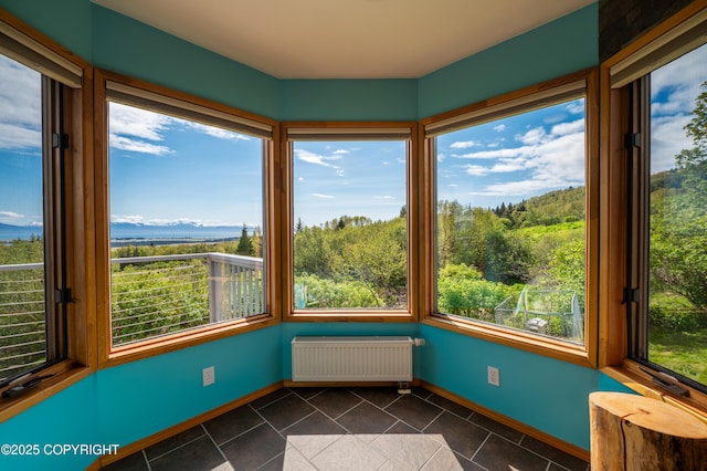 2435 Paradise Pl, Homer, AK 99603 - unfurnished sunroom featuring radiator heating unit, tile patterned floors, plenty of natural light, and baseboards