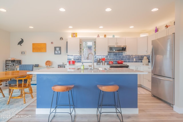 437 W Fairview Ave, Homer, AK 99603 - kitchen featuring appliances with stainless steel finishes, a sink, a breakfast bar, light countertops, and recessed lighting