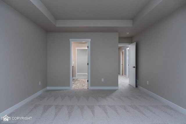 unfurnished bedroom featuring a tray ceiling, carpet floors, and baseboards