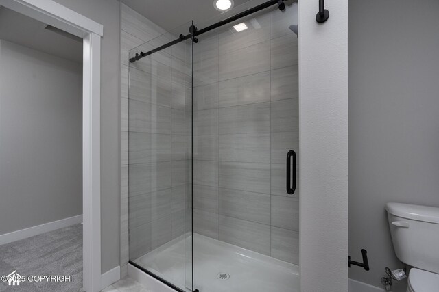 full bath featuring toilet, a shower stall, and baseboards