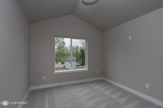 spare room with light colored carpet, lofted ceiling, and baseboards