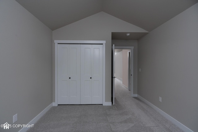 unfurnished bedroom with carpet, lofted ceiling, baseboards, and a closet