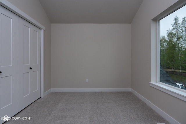 unfurnished bedroom with light carpet, a closet, and baseboards