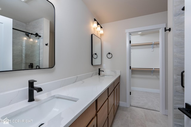 full bath featuring a shower stall, a walk in closet, double vanity, and baseboards