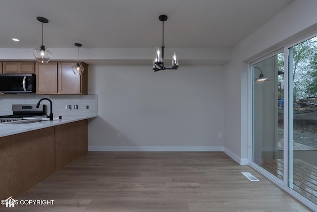 kitchen with stainless steel appliances, decorative backsplash, baseboards, light countertops, and decorative light fixtures