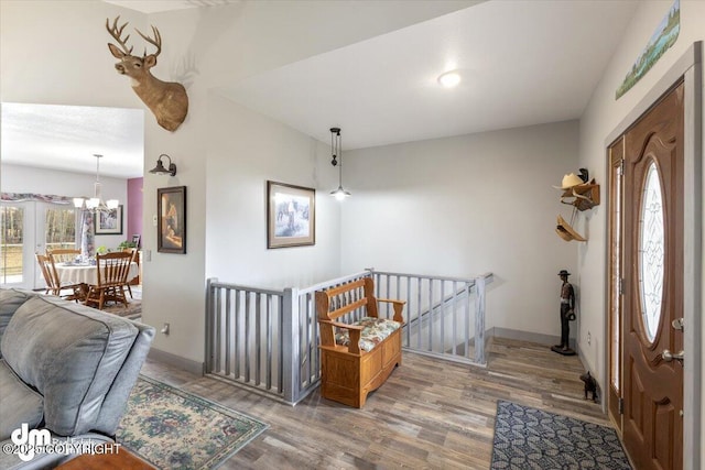 entryway with baseboards, wood finished floors, and a notable chandelier