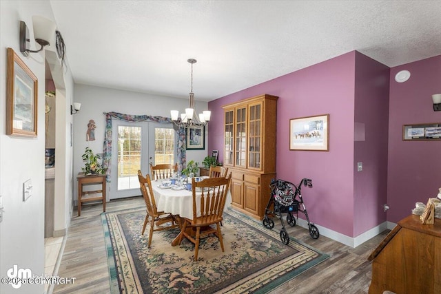 dining area with baseboards, an inviting chandelier, french doors, and light wood finished floors