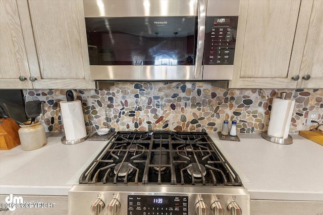 kitchen with backsplash, light brown cabinetry, and appliances with stainless steel finishes