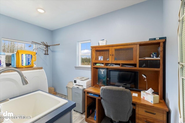 office space featuring a sink and light wood-style flooring