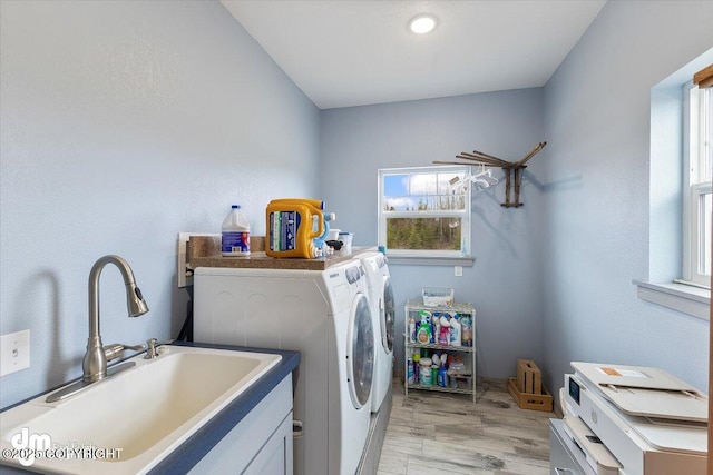 clothes washing area featuring laundry area, a sink, a healthy amount of sunlight, and washer and clothes dryer
