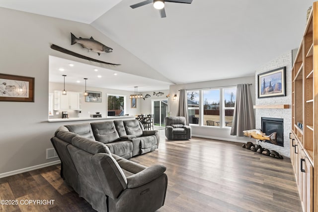 living area featuring a fireplace, dark wood-type flooring, visible vents, vaulted ceiling, and plenty of natural light