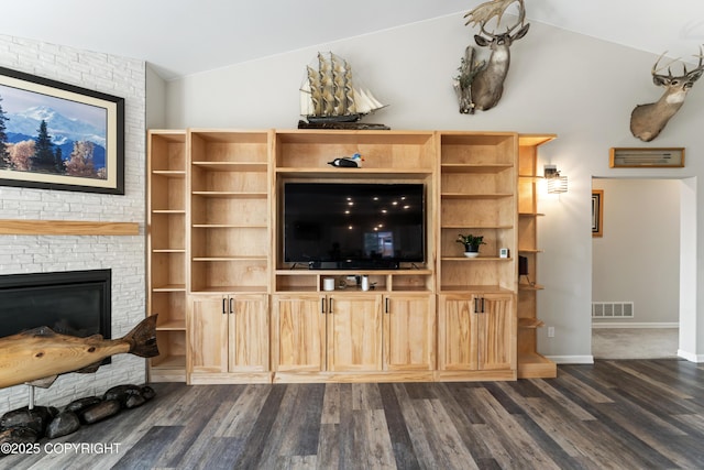 unfurnished living room with dark wood-style floors, a large fireplace, visible vents, and vaulted ceiling