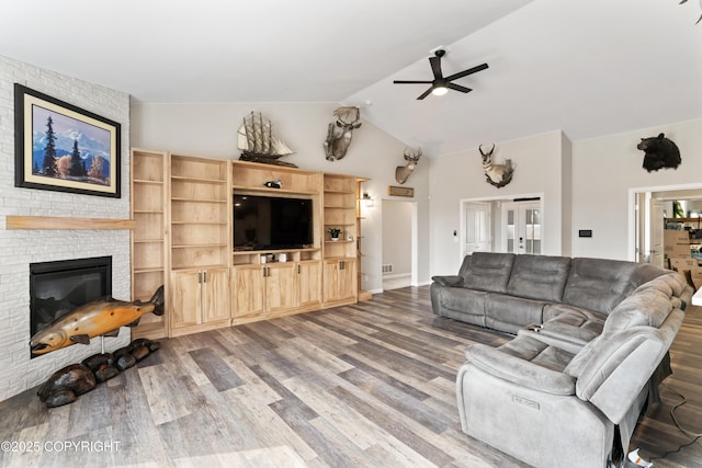 living area featuring a fireplace, wood finished floors, ceiling fan, and lofted ceiling