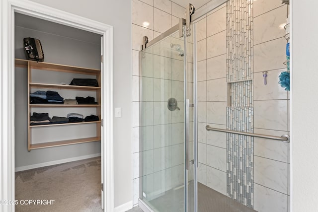 full bathroom featuring a stall shower, a walk in closet, and baseboards