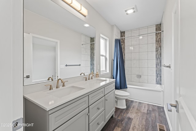 full bathroom with visible vents, toilet, double vanity, and a sink