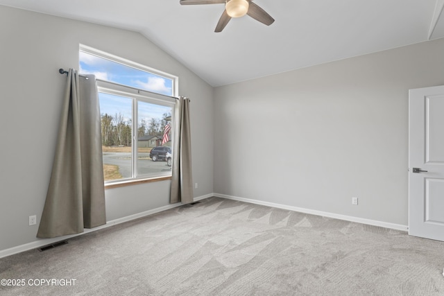 carpeted spare room featuring lofted ceiling, visible vents, a ceiling fan, and baseboards