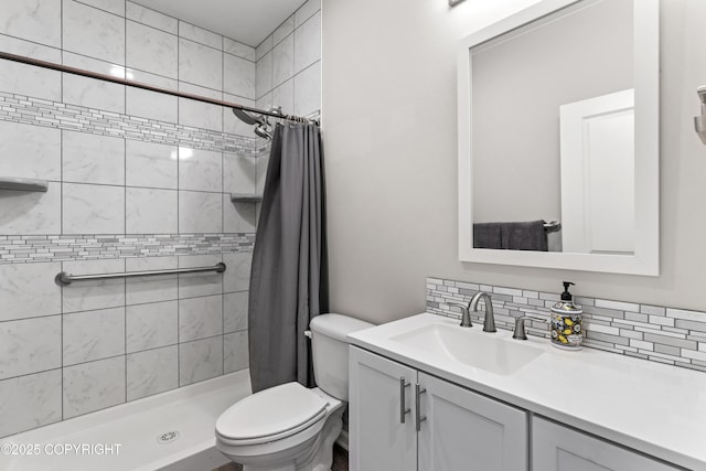bathroom with vanity, toilet, a shower stall, and backsplash