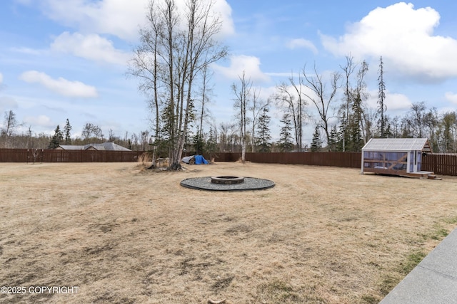 view of yard with an outdoor fire pit, a fenced backyard, and an outbuilding