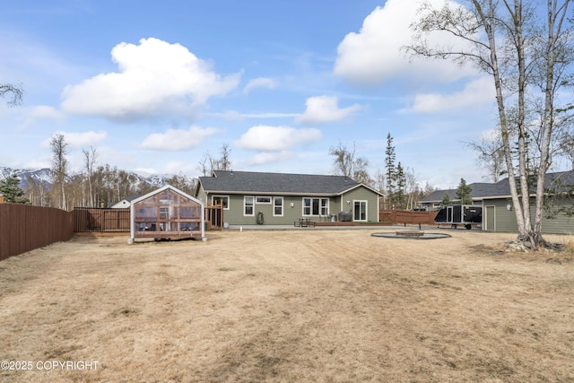 back of property featuring fence, an outbuilding, and a greenhouse