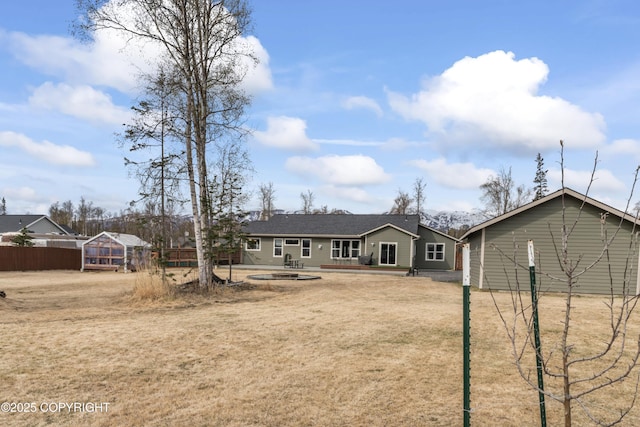 rear view of property featuring an outbuilding, fence, and a greenhouse