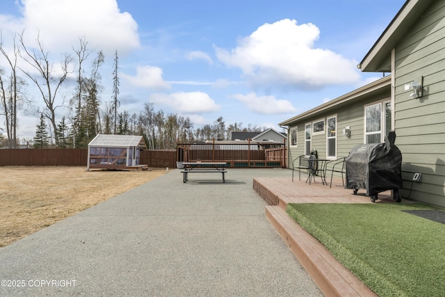 view of patio with a fenced backyard, grilling area, an outbuilding, a wooden deck, and a shed