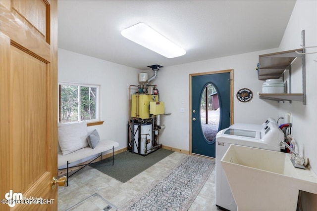 laundry area with laundry area, washing machine and dryer, a sink, and water heater