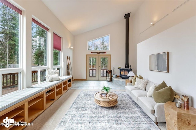 interior space with french doors, high vaulted ceiling, a healthy amount of sunlight, and a wood stove