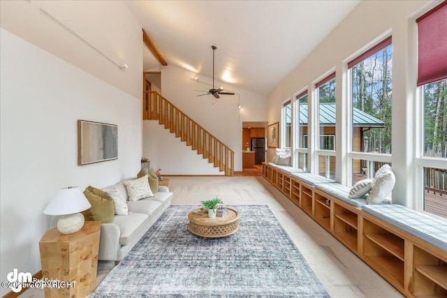 living area with a ceiling fan, stairway, high vaulted ceiling, baseboards, and carpet flooring