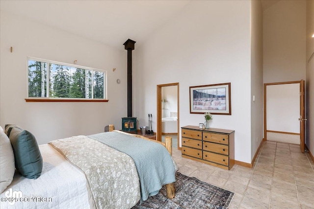 bedroom with high vaulted ceiling, baseboards, and a wood stove