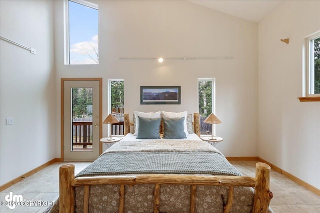 bedroom featuring baseboards, multiple windows, light tile patterned flooring, and access to outside