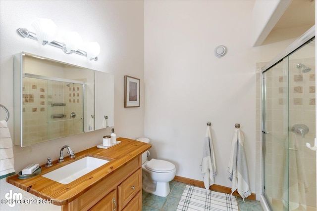 bathroom with vanity, tile patterned flooring, toilet, baseboards, and a stall shower