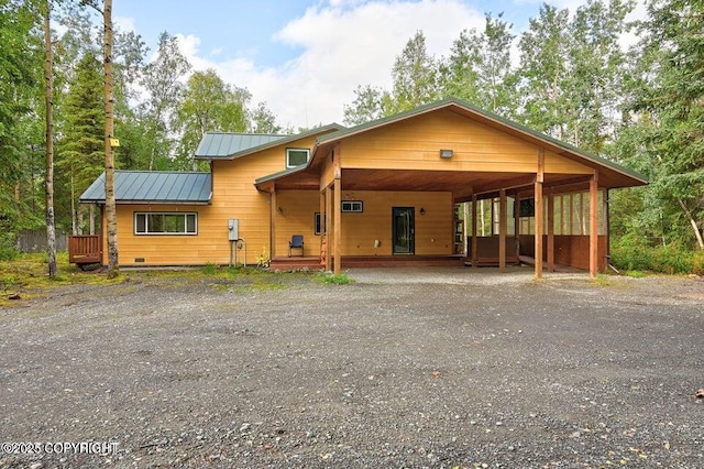 rustic home with a standing seam roof, driveway, metal roof, and a carport