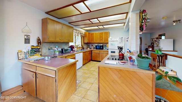 kitchen featuring light countertops, decorative columns, a peninsula, tasteful backsplash, and black appliances