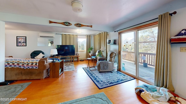 living area with an AC wall unit and wood finished floors