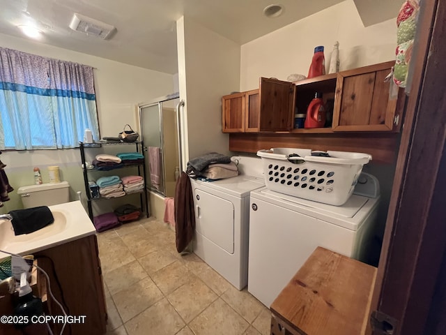 washroom with washing machine and dryer, cabinet space, visible vents, and light tile patterned floors