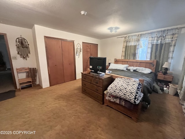 bedroom with two closets, carpet flooring, and a textured ceiling