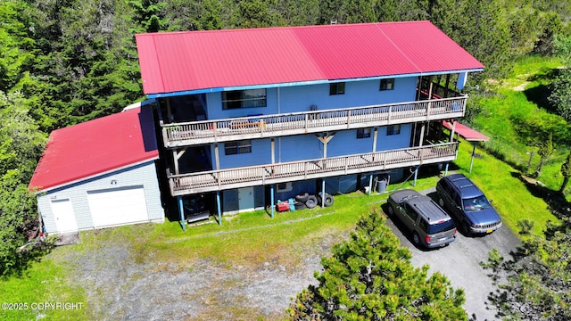 exterior space featuring dirt driveway, a garage, a balcony, a wooden deck, and metal roof