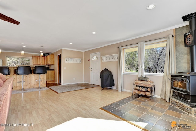 living room featuring a wood stove, baseboards, crown molding, recessed lighting, and ceiling fan