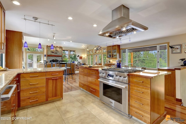 16900 Ransom Ridge Rd, Anchorage, AK 99516 - kitchen with island range hood, stainless steel appliances, brown cabinets, light stone countertops, and recessed lighting