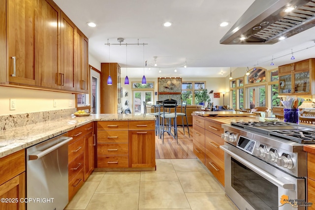 16900 Ransom Ridge Rd, Anchorage, AK 99516 - kitchen with stainless steel appliances, extractor fan, rail lighting, open floor plan, and light stone countertops