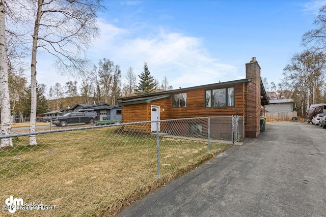 10209 Colville St, Eagle River, AK 99577 - view of front of house with fence private yard, aphalt driveway, a front yard, and a chimney