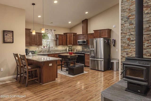 3604 N Copperspike St, Wasilla, AK 99623 - kitchen with appliances with stainless steel finishes, a peninsula, a sink, a wood stove, and light stone counters