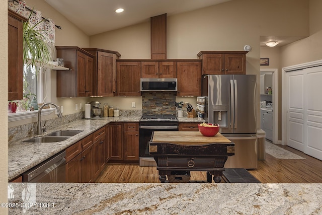 3604 N Copperspike St, Wasilla, AK 99623 - kitchen with appliances with stainless steel finishes, a sink, lofted ceiling, light wood-type flooring, and light stone counters